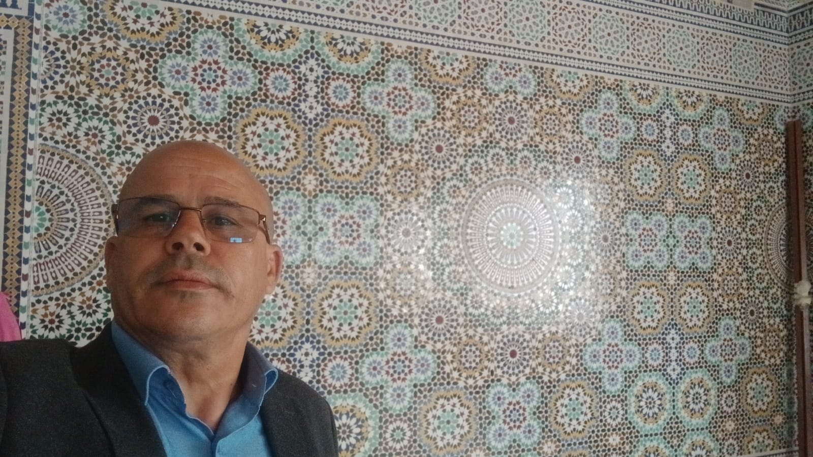 Maâlem DTAT devant un mur de zellige beldi